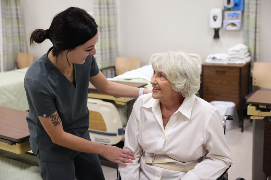 Nursing Assistant helping elderly woman in chair