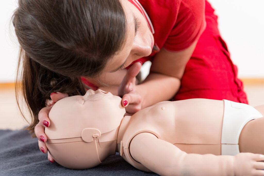 Woman checking breathing of an infant-sized CPR training dummy