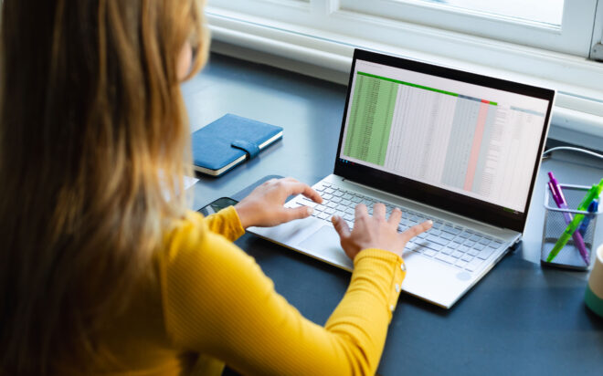 Woman working on laptop with spreadsheet document open