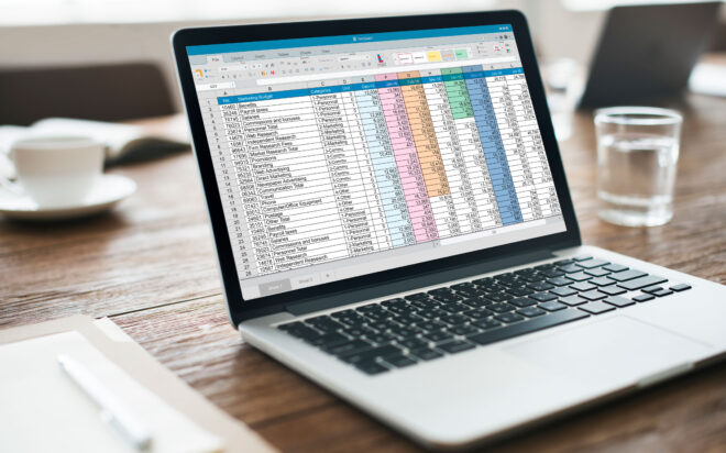 Laptop on table showing on-screen spreadsheet filled with budgeting numbers.